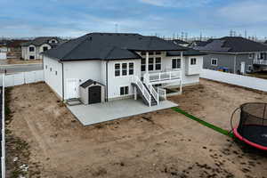 Rear view of property featuring a wooden deck, a patio, and a trampoline