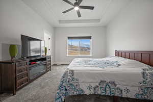 Bedroom featuring light carpet, a tray ceiling, and ceiling fan