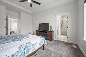 Carpeted bedroom featuring ensuite bath and ceiling fan