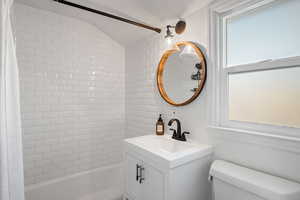 Full bathroom featuring a healthy amount of sunlight, toilet, vanity, and shower / bath combo