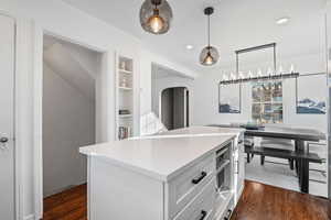 Kitchen featuring decorative light fixtures, a center island, dark hardwood / wood-style flooring, built in features, and white cabinets