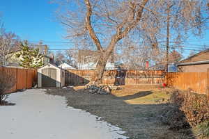 Yard covered in snow with a storage unit