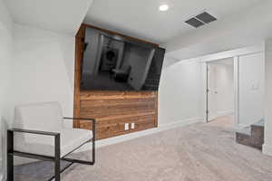 Sitting room with washer / dryer, wooden walls, and light colored carpet