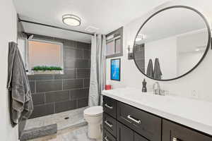 Bathroom featuring vanity, toilet, curtained shower, and a textured ceiling