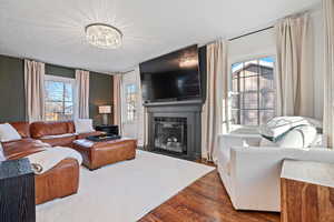 Living room featuring a fireplace, dark hardwood / wood-style floors, a chandelier, and a textured ceiling