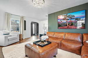 Living room with hardwood / wood-style floors, a notable chandelier, and a textured ceiling