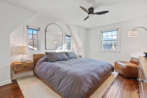 Bedroom featuring multiple windows, dark wood-type flooring, and ceiling fan