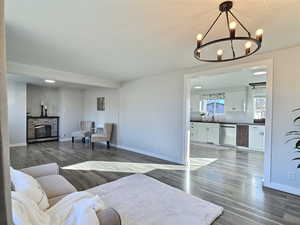 Living room with sink, a chandelier, dark hardwood / wood-style floors, and a stone fireplace