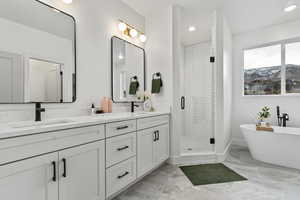 Pathroom featuring floor-to-ceiling tiled shower with separate freestanding bath tub below a mountain view, double vanity, and walk-in closet