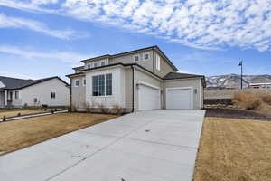 View of front of home with extra-length three-car garage, a mountain view, and a front lawn that looks nicer in Spring