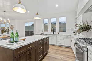 Kitchen featuring sink, decorative light fixtures, stainless steel gas range, and white cabinets