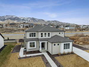 East-facing view of front of property featuring a mountain view and a front lawn, fully landscaped