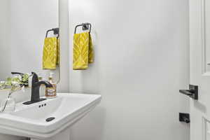 Half bath with sink and toilet, off the kitchen next to the garage