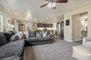 Carpeted living room with ceiling fan, sink, a textured ceiling, and a wealth of natural light