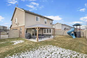 Rear view of property featuring a lawn and a patio