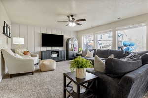 Carpeted living room with ceiling fan and a textured ceiling