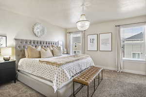 Carpeted bedroom with an inviting chandelier and a textured ceiling