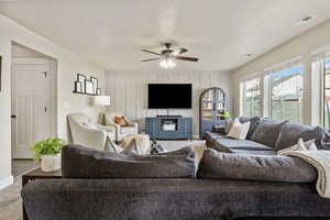 Living room featuring ceiling fan, carpet floors, and a textured ceiling