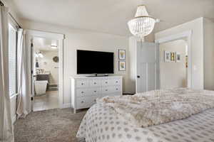 Bedroom with multiple windows, a notable chandelier, light carpet, and a textured ceiling