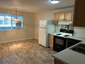 Kitchen featuring light brown cabinetry, sink, hanging light fixtures, white fridge, and electric range