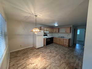 Kitchen with pendant lighting, sink, electric stove, white refrigerator, and light brown cabinets