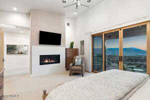 Bedroom with an inviting chandelier, access to exterior, and a fireplace