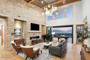 Living room featuring a fireplace, wood-type flooring, beam ceiling, and a high ceiling