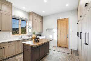 Kitchen featuring light brown cabinetry, a center island, sink, and backsplash