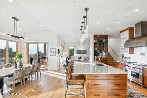 Kitchen featuring premium range hood, an island with sink, high end range, and decorative light fixtures