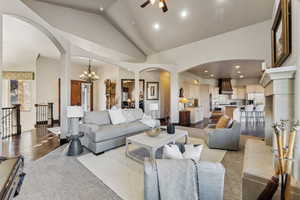 Living room featuring lofted ceiling and ceiling fan with notable chandelier