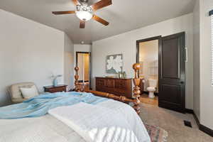 Carpeted bedroom with ensuite bathroom and ceiling fan