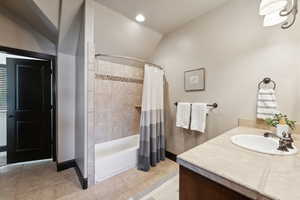 Bathroom with shower / tub combo, vanity, tile patterned flooring, and vaulted ceiling