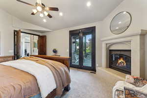 Carpeted bedroom featuring access to exterior, vaulted ceiling, a premium fireplace, and ceiling fan