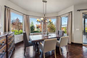 Dining room featuring a healthy amount of sunlight, a notable chandelier, and dark hardwood / wood-style flooring