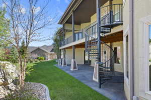 View of green lawn featuring stairs, a patio, and a balcony