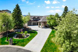 View of front of house with curved driveway, a front lawn, and an attached garage