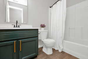 Full bathroom with vanity, wood-type flooring, shower / bath combination with curtain, and toilet