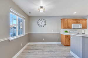 Kitchen with white appliances, light hardwood / wood-style floors, and decorative backsplash