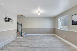 Empty room with light hardwood / wood-style flooring and a textured ceiling