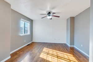 Spare room featuring dark hardwood / wood-style floors, a textured ceiling, and ceiling fan