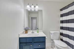 Bathroom featuring a shower with curtain, vanity, and toilet