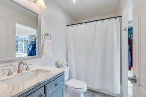 Bathroom with vanity, toilet, and curtained shower