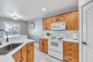 Kitchen with white appliances, light hardwood / wood-style floors, and sink