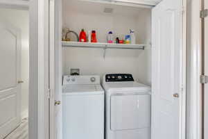 Clothes washing area with washing machine and clothes dryer and light wood-type flooring