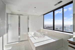 Bathroom featuring a relaxing tiled tub, vanity, and tile patterned floors