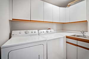 Washroom with cabinets, separate washer and dryer, and sink