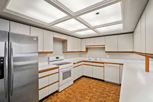 Kitchen with white appliances, sink, light parquet floors, and white cabinets