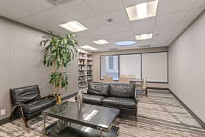 Carpeted living room with a paneled ceiling and built in features