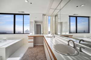 Bathroom featuring vanity, tiled tub, and tile patterned flooring