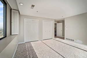 Unfurnished bedroom with multiple closets and carpet floors